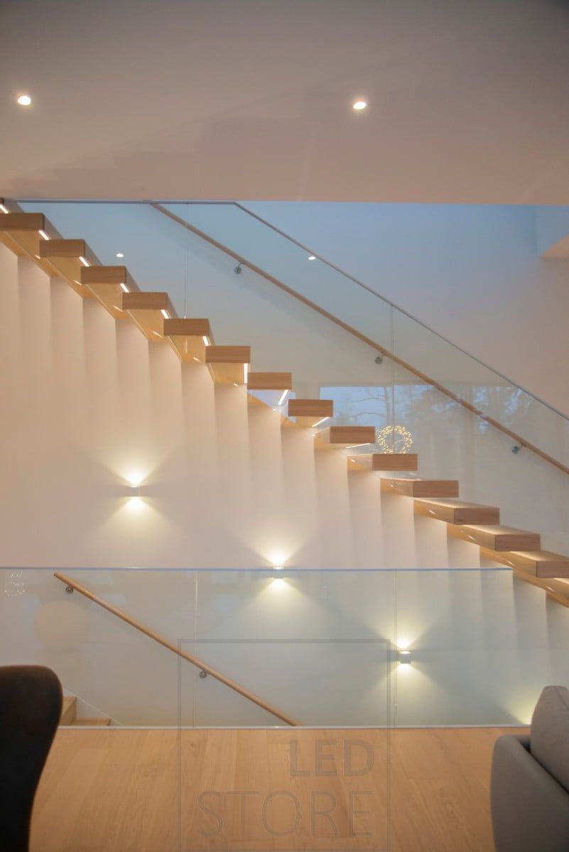 Beautiful airy staircase illuminated with led strips and CUBIC wall lights.